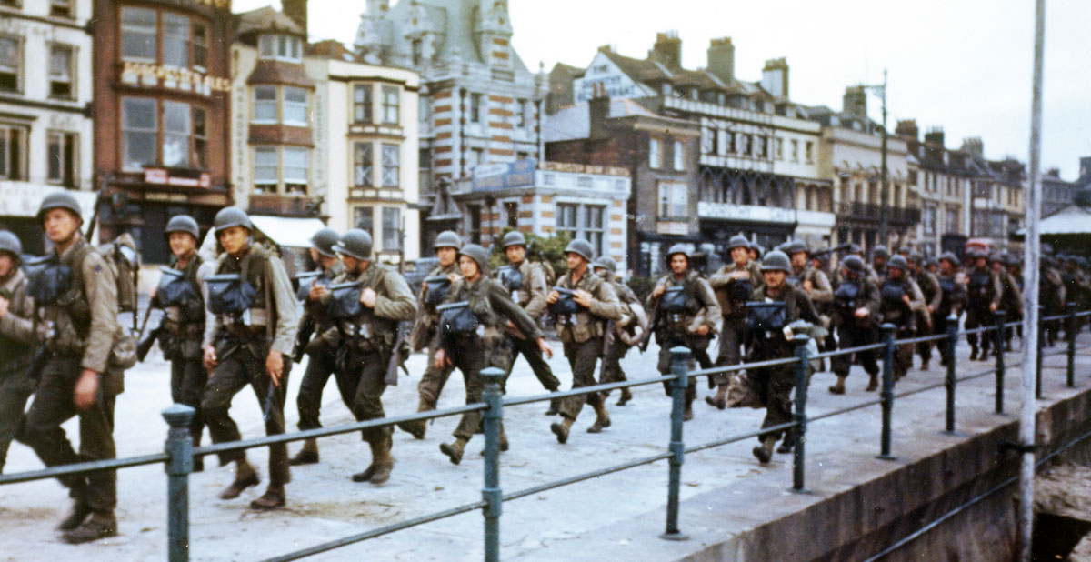 Troops march through an English seaside town toward their ships before D-Day. Troops march through an English seaside town toward their ships before D-Day.